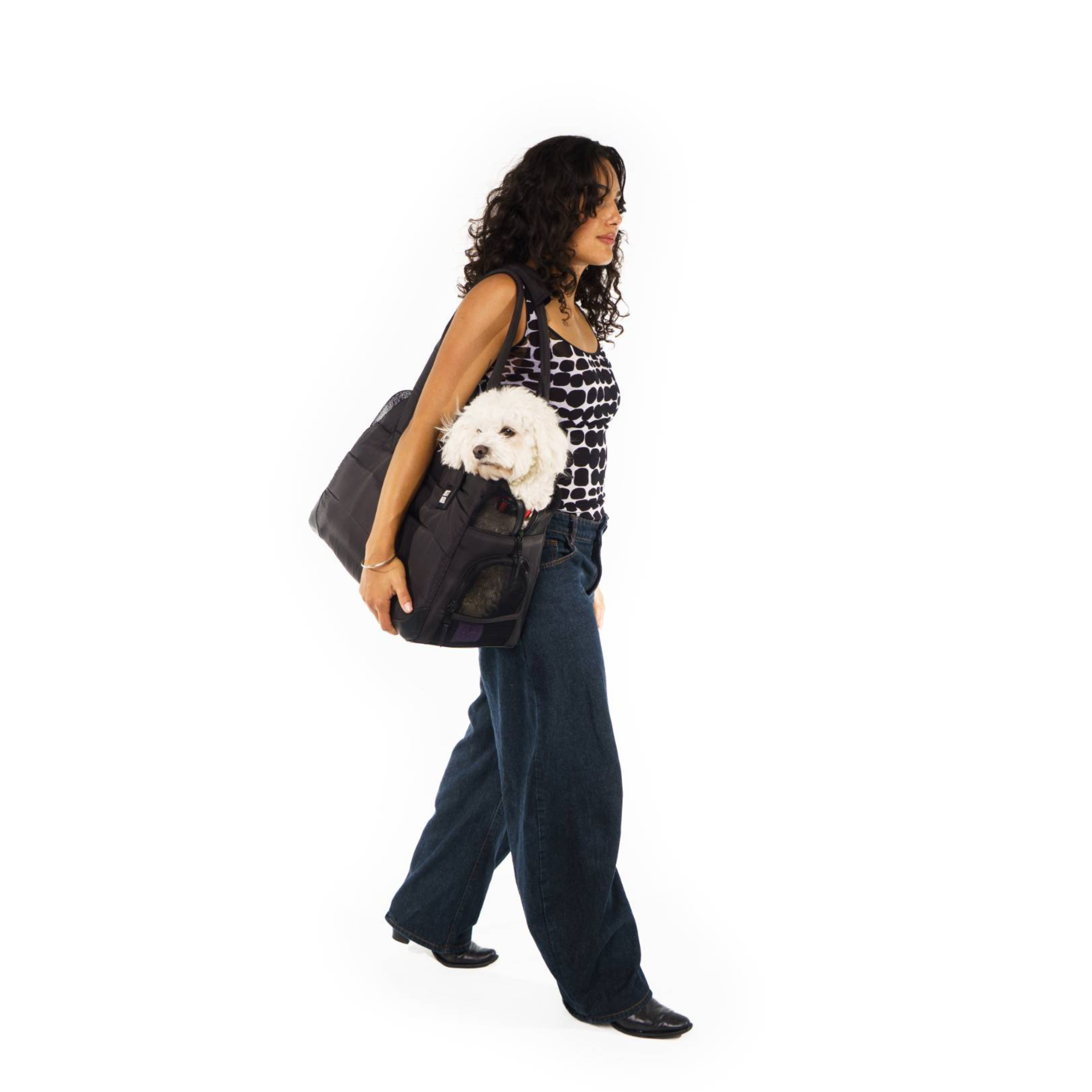 Woman carrying a Just Fred black Companion Tote dog carrier with a small white dog inside on a white background