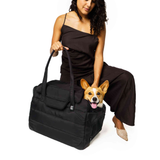 Woman holding a black Just Fred Companion Tote pet  dogcarrier with a corgi dog peeking out of the top mesh opening, on a white background