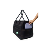 Black Just Fred Subway tote pet dog carrier bag with a hand placing a tablet inside the side pocket, on a white background
