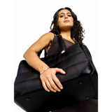 Woman holding a black Just Fred Subway tote dog carrier bag showing vegan leather base, against a white background