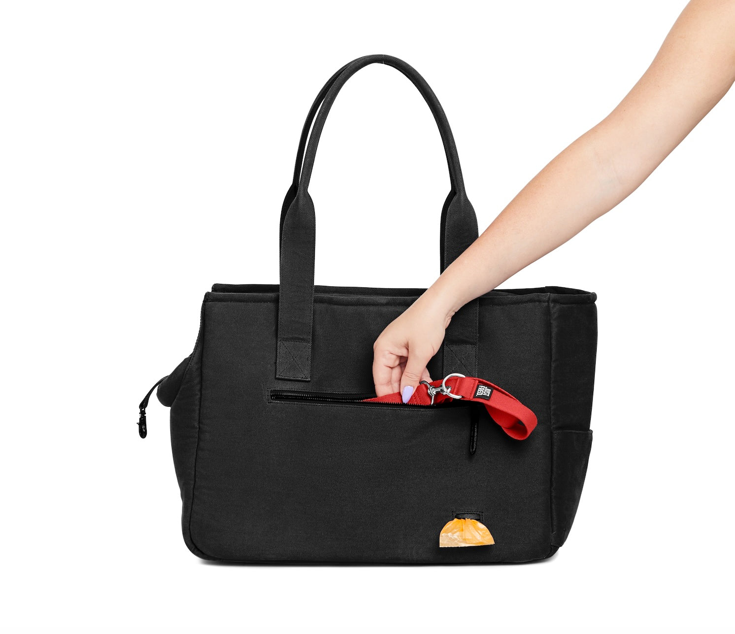 Woman's arm putting a leash into the side pocket of the black Just Fred x Fem World by Ally Lindsay Weekend Tote dog pet carrier, on a white background