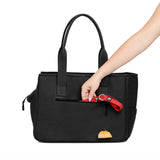 Woman's arm putting a leash into the side pocket of the black Just Fred x Fem World by Ally Lindsay Weekend Tote dog pet carrier, on a white background