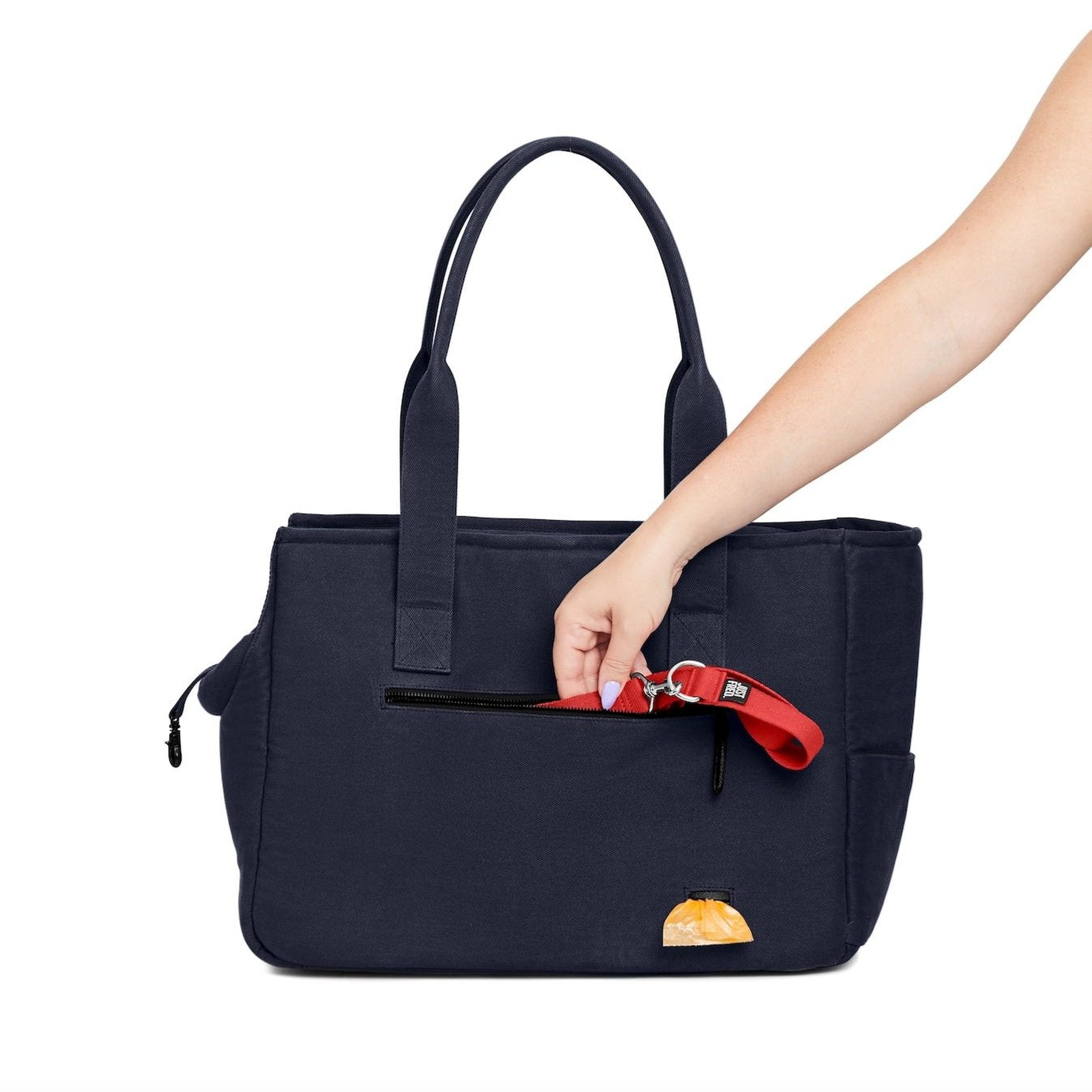 Navy Just Fred Weekend tote dog carrier bag with a womans arm demonstrating the back pocket and poo bag dispenser, on a white background