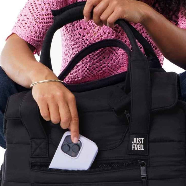 Woman opening a black pet carrier with a small white dog sitting next to her on a white background