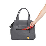 A woman's arm places a red Just Fred leash into a zipped back pocket in a Just Fred gray Destination Tote dog carrier., on a white background